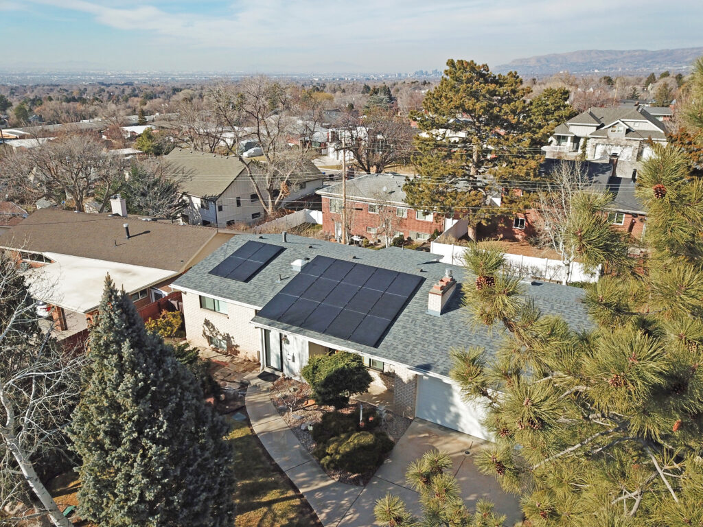A modern residential home in Utah featuring a high-efficiency rooftop solar panel array installed on a dark shingled roof under a clear blue sky, illustrating clean energy production in the Intermountain West.