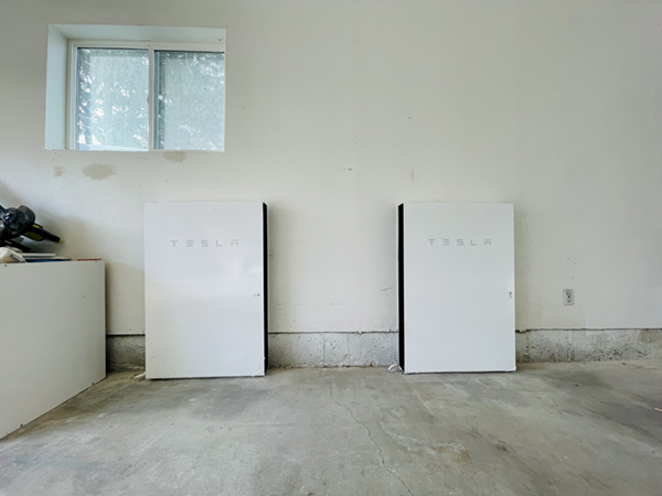 Tesla home battery set against a garage wall